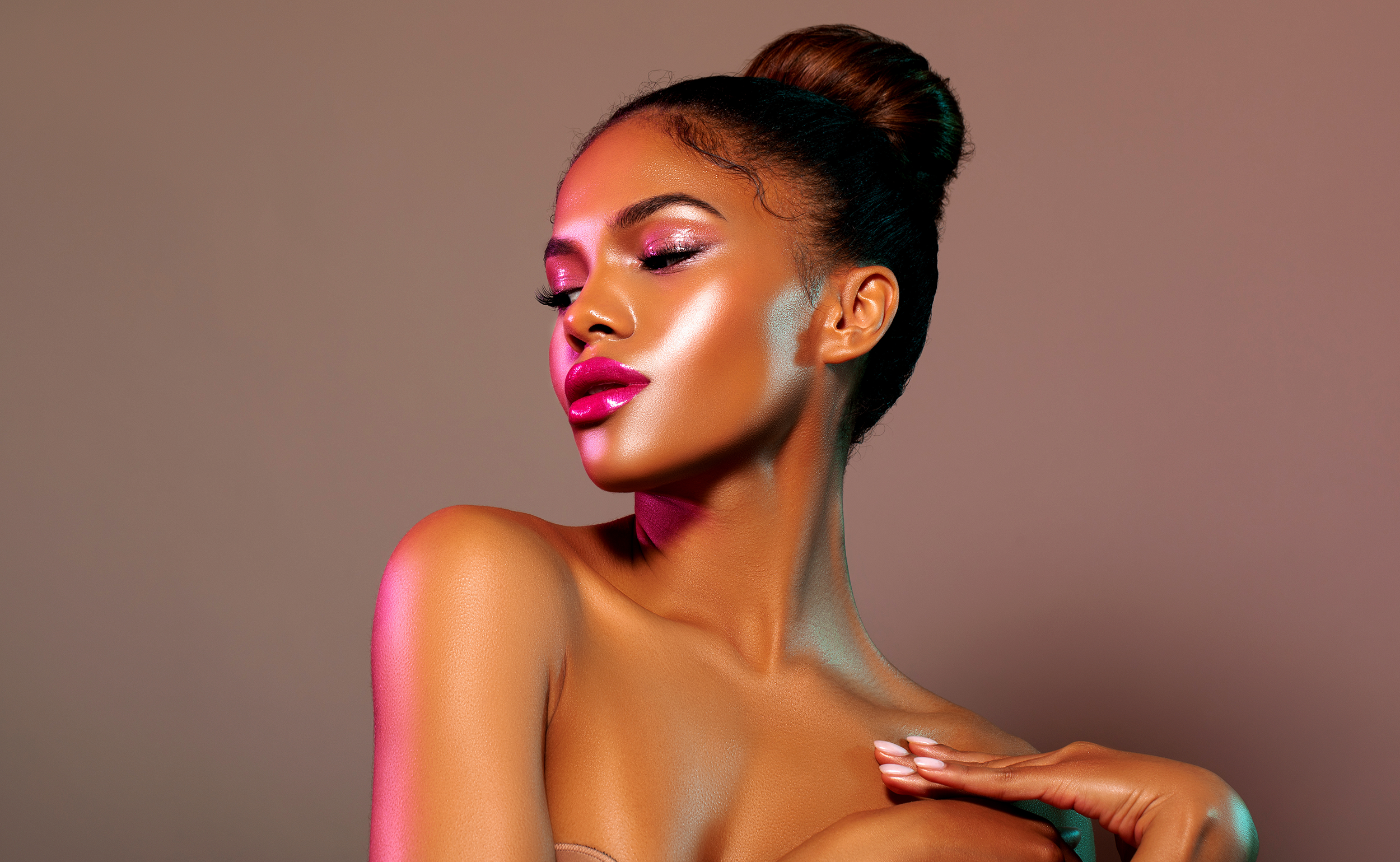 Portrait of a woman with vibrant makeup and a stylish bun on a brown background for the Mielle Organics Shopify website design by The Chicago web Co. 